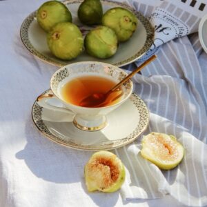 Image of a cup of tea and a plate of figs on a linen table spread.